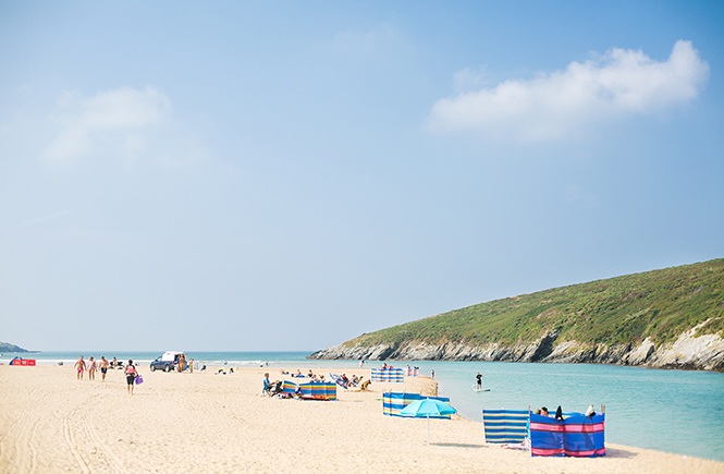 A number of colourful windbreaks next to the water at Crantock beach