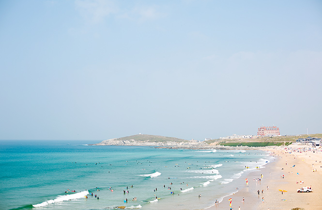 Looking down the stretch of sand and sea at Fistral beach in Newquay where surfers surf and people lie on the beach