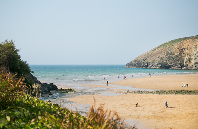 People walking along the sheltered beach at Mawgan Porth