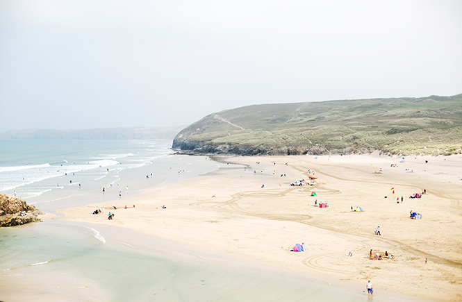 The stretching sands at Perranporth beach with the headland in the background