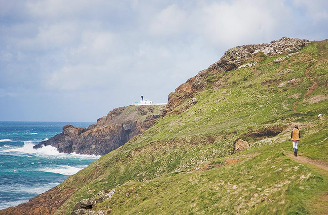 Someone walking along the cliffs towards Pendeen Lighthouse near St Ives in West Cornwall