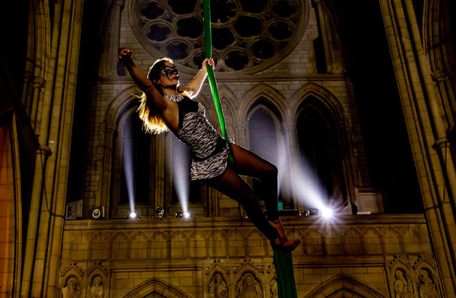 A circus performer hanging from the ceiling at the Cathedral Masquerade