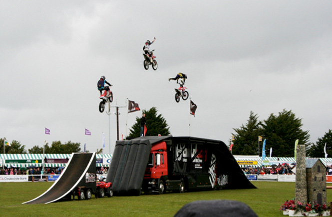 Thee people on motorbikes performing a stunt in the main ring at Royal Cornwall Show