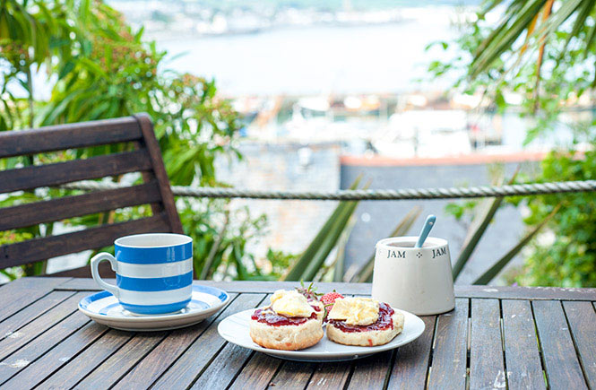 A Cornish cream tea on a table looking out over a beautiful town in Cornwall