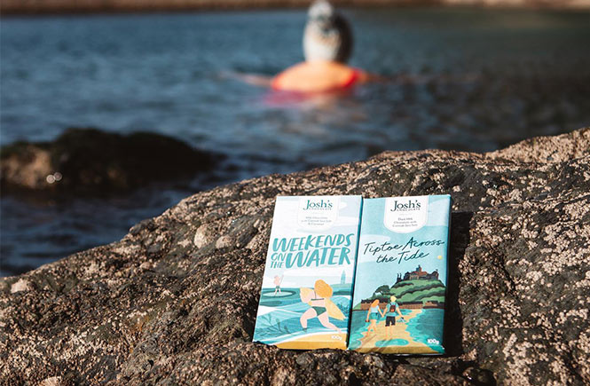 Two of the beautifully wrapped Josh's Chocolate bars sitting on the rocks by the sea