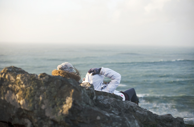 Two people storm watching from Cornish cliffs