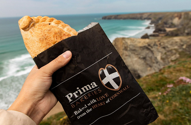 Some holding a Cornish pasty by Prima Bakeries while walking on the Cornish coastal paths