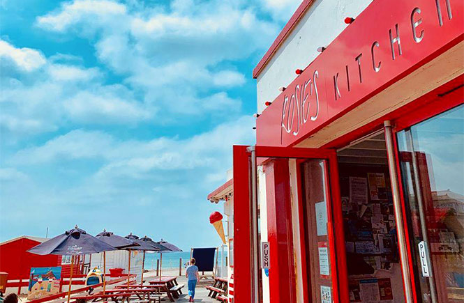 The bright red signage and beautiful seating area at Rosie's Kitchen, which overlooks Crooklets beach in Bude