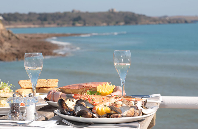 Plates full of seafood and glasses of wine out on the terrace at Hooked on the Rocks over looking the sea at Swanpool