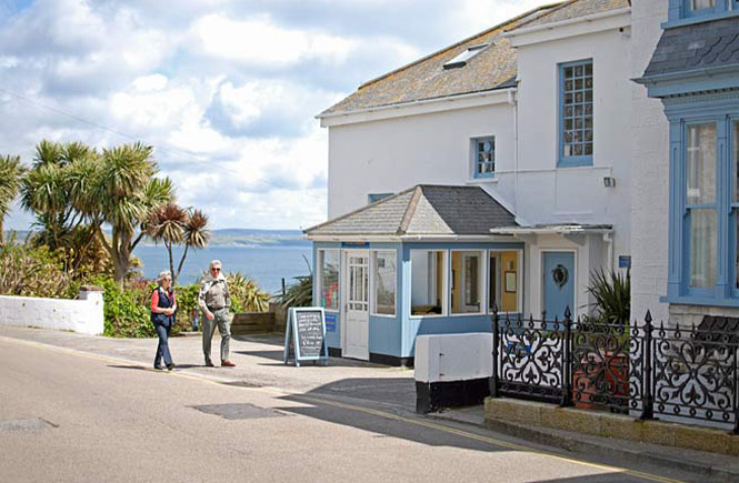 A couple walking past the pretty Old Coastguard Hotel, one of the best places to eat in Mousehole