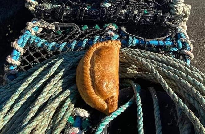 A Cornish pasty from Aunty Mays sat on some lobster pots and fishing nets in Newlyn