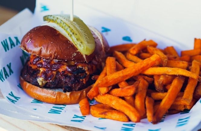 A burger and sweet potato fries in WAX paper