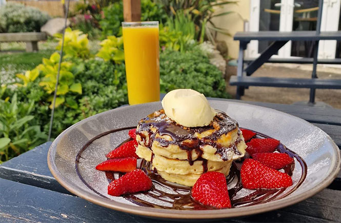 A stack of buttermilk pancakes topped with chocolate sauce and strawberries at No.4 Breakfast & Bistro