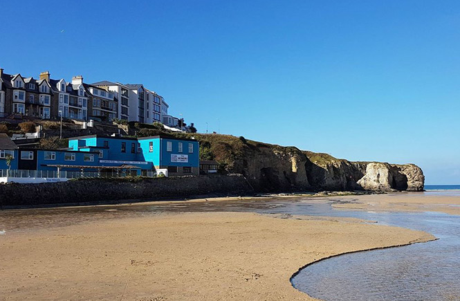 The bright blue exterior of Seiners Arms perched just above the sands of Perranporth beach