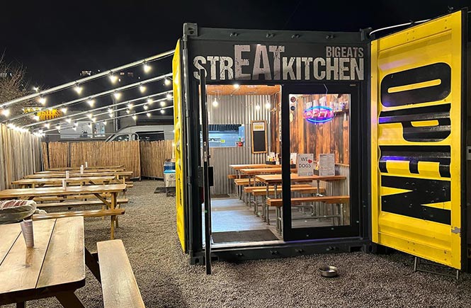 The shipping container that holds the delicious burgers from BigEats, surrounded by outdoor seating and fairy lights