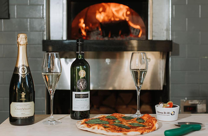 Pizza and Camel Valley wine in front of the wood-fired pizza oven at The Corner Deli