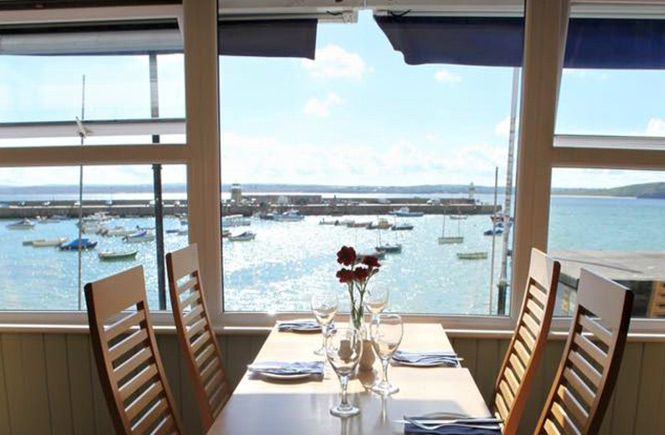 A laid table in front of a window that looks out over St Ives harbour