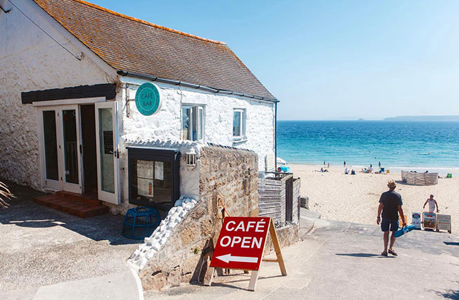 The white exterior of the Porthgwidden Beach Cafe right next to the beach