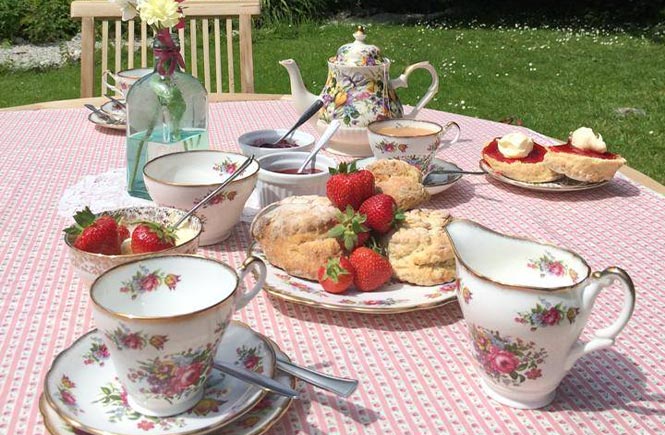 A selection of vintage china alongside scones, jam and clotted cream at Miss V's, one of the best cream teas in Cornwall