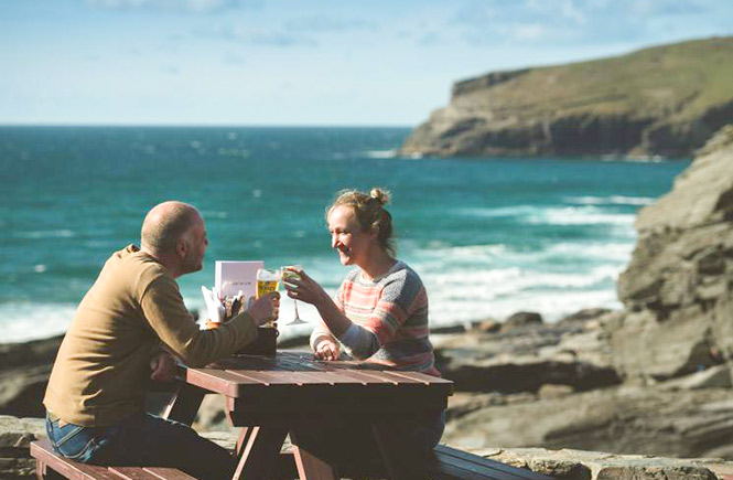 Two people enjoying drinks in the beer garden overlooking the sea at The Port William