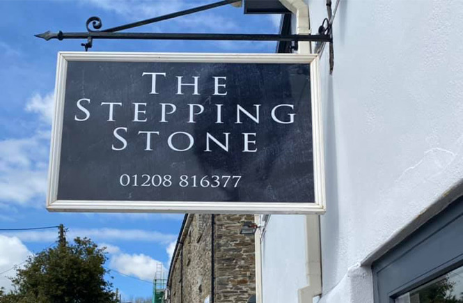 A sleek sign hanging outside of The Stepping Stone in Wadebridge