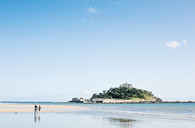 People walking along Marazion beach with St Michael's Mount behind