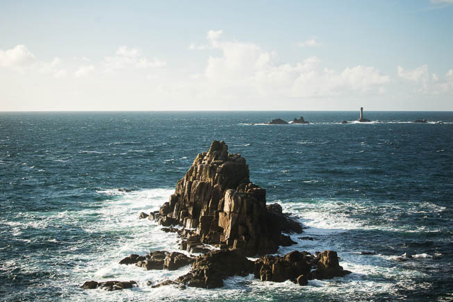 The rocks and lighthouse at Land's End surrounded by waves