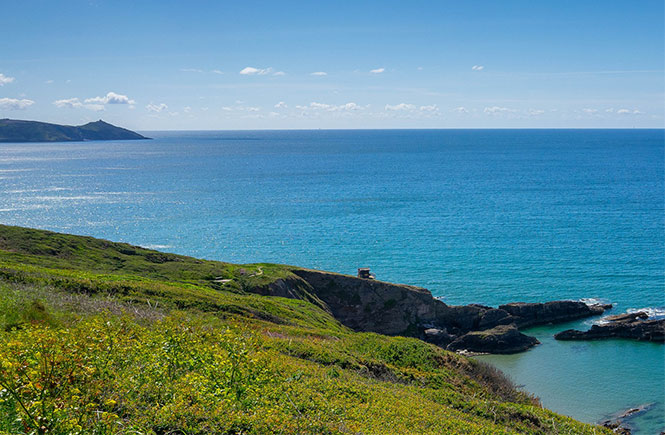 Looking out over the green cliffs and blue sea at Rame Head in Cornwall