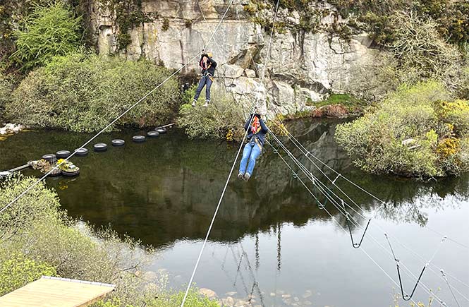 People zip-lining above the quarry at the Zip Wire Safari at Via Ferrata in Cornwall