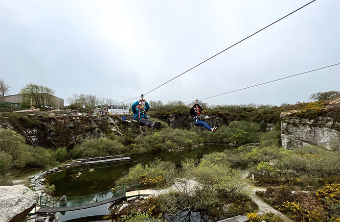 Two people swinging along the Zip Wire Safari at Via Ferrata in Cornwall