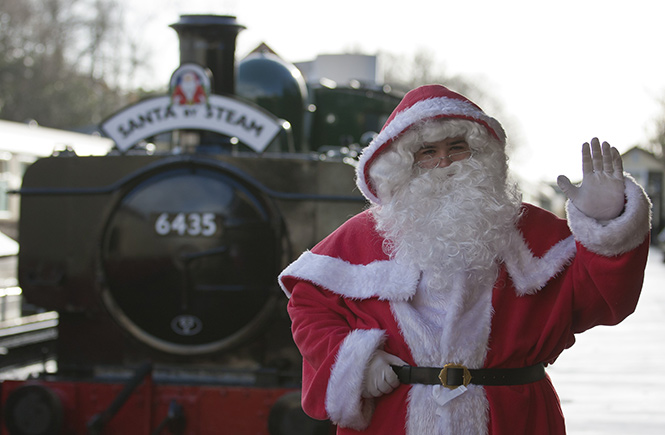 Father Christmas standing in front of a steam train at Bodmin & Wenford Railway