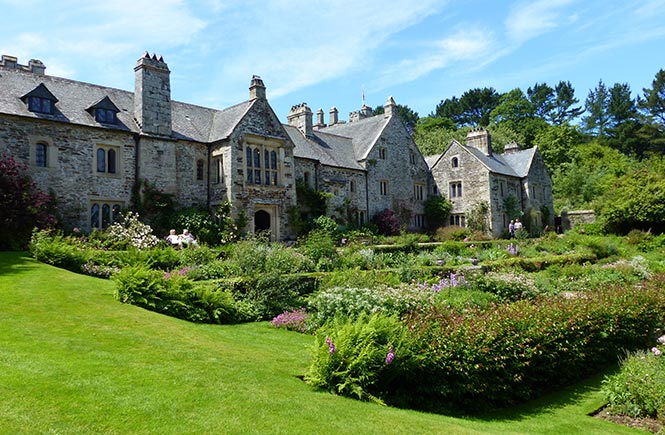 The pretty National Trust property at Cotehele with green gardens and a blue sky
