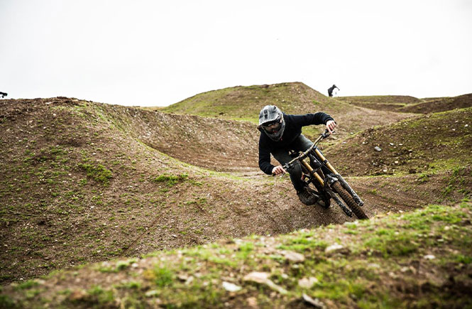 Someone wearing a full face helmet riding down an off-road trail in Cornwall at Woody's Bike Park