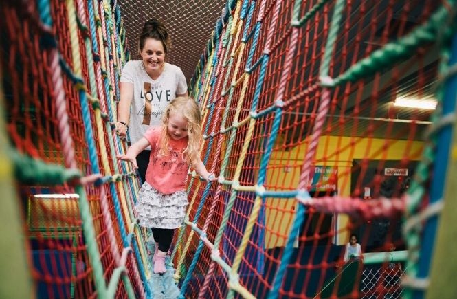 A mother and daughter on a brightly coloured rope bridge at Kidzworld Adventure Play