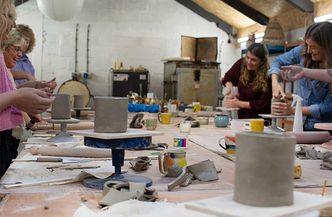 People around a table making pottery mugs with Wedge Studio in Newquay