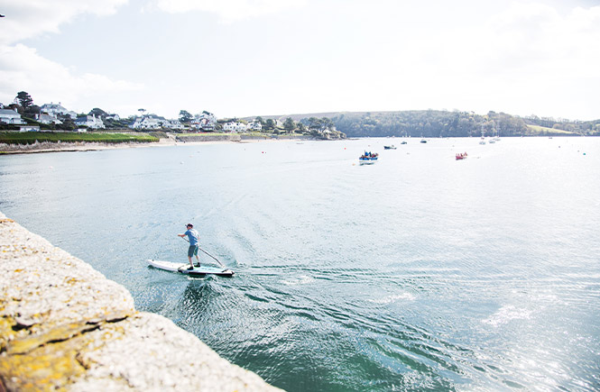 Someone paddleboarding along the harbour in St Mawes