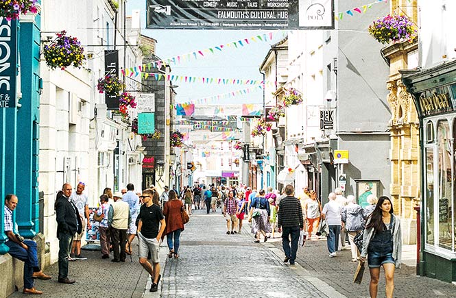 The bustling Falmouth highstreet with bunting having colourfully above the cobbled street