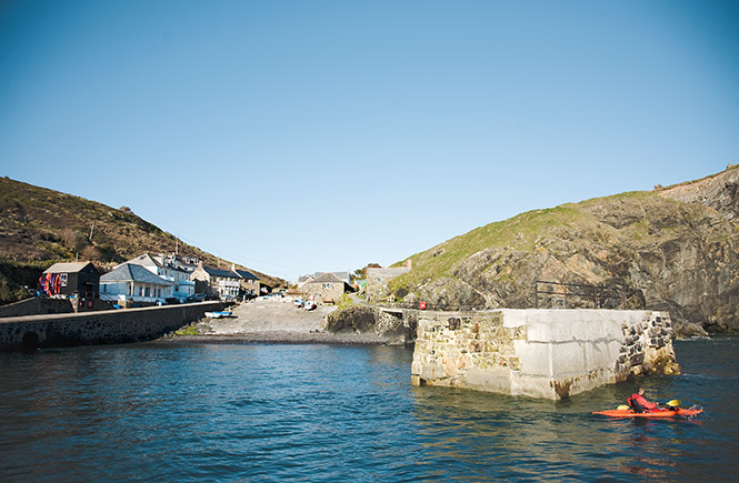 A kayaker paddling past the harbour at Mullion Cove, one of the many things to do in and around Mullion