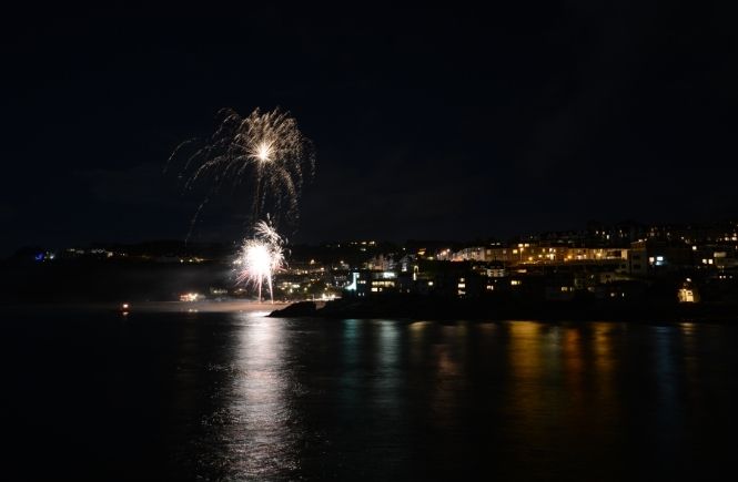 Fireworks over St Ives in the dark with reflections on the water