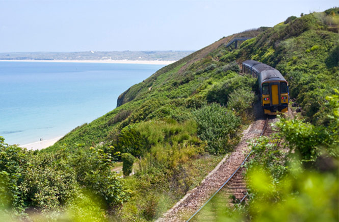 The train coming into St Ives from Carbis Bay with the clear blue sea in the background