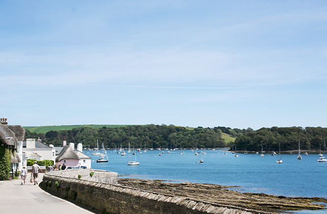 A couple walking along the waterside road in St Mawes