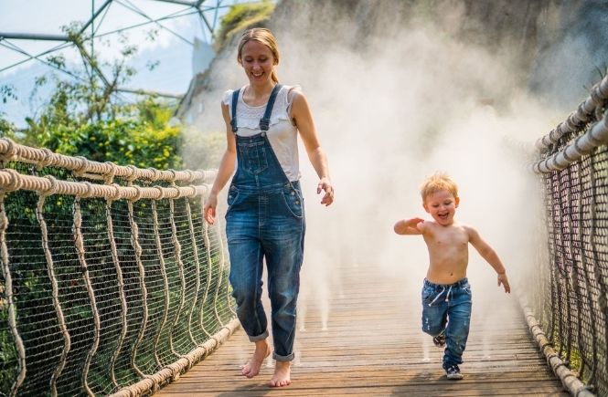 Woman and child running over the steam bridge in the Eden Project's Rainforest Biome