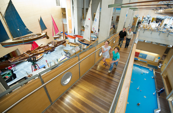 A family walking through the display gallery at the Maritime Museum with boats all around
