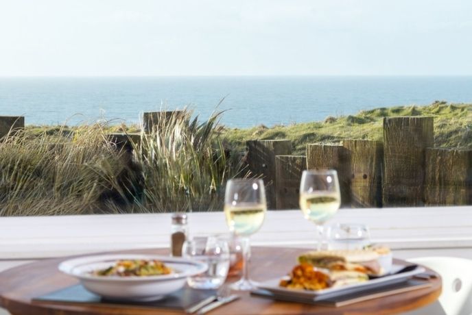 Food and wine on an outdoor table with the sea in the background at Beachcomber restaurant
