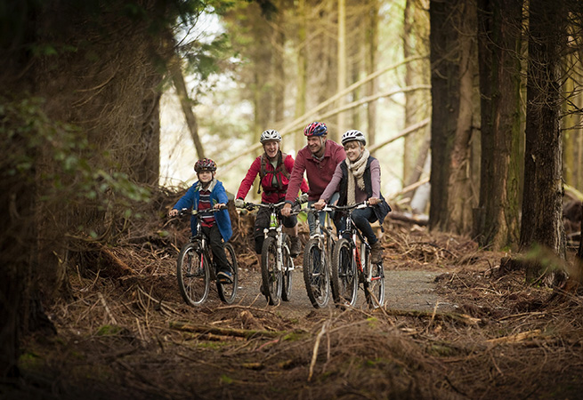 A family cycling through the woods in Cornwall