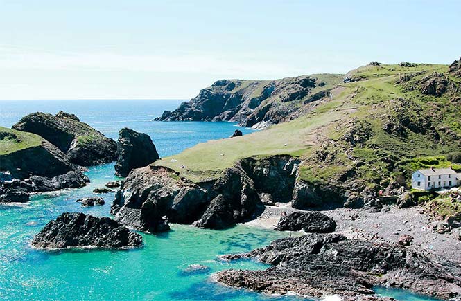 Beautiful bright blue waters and the iconic cliffs and rock formations at Kynance Cove, one of the best places for a picnic in Cornwall