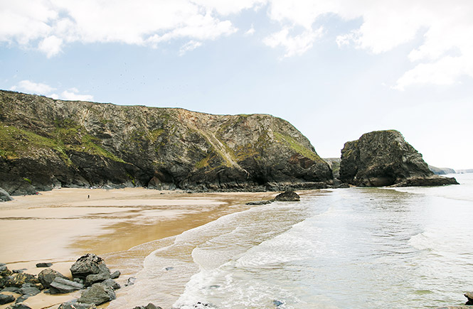 Looking out over the golden sands and looming cliffs at Pentire beach in Cornwall