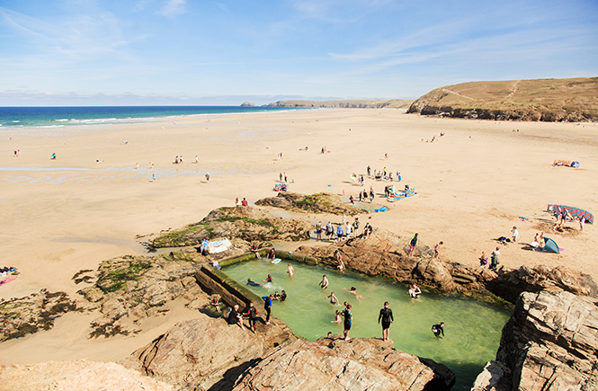 People on the dog friendly sandy beach and chapel rock sea pool at Perranporth, Cornwall