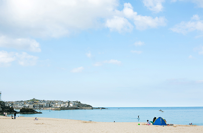 People sitting on the beach and swimming at Porthminster in St Ives
