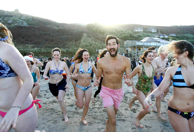 A crowd of people running into the sea for the Christmas Day swim at Sennen beach